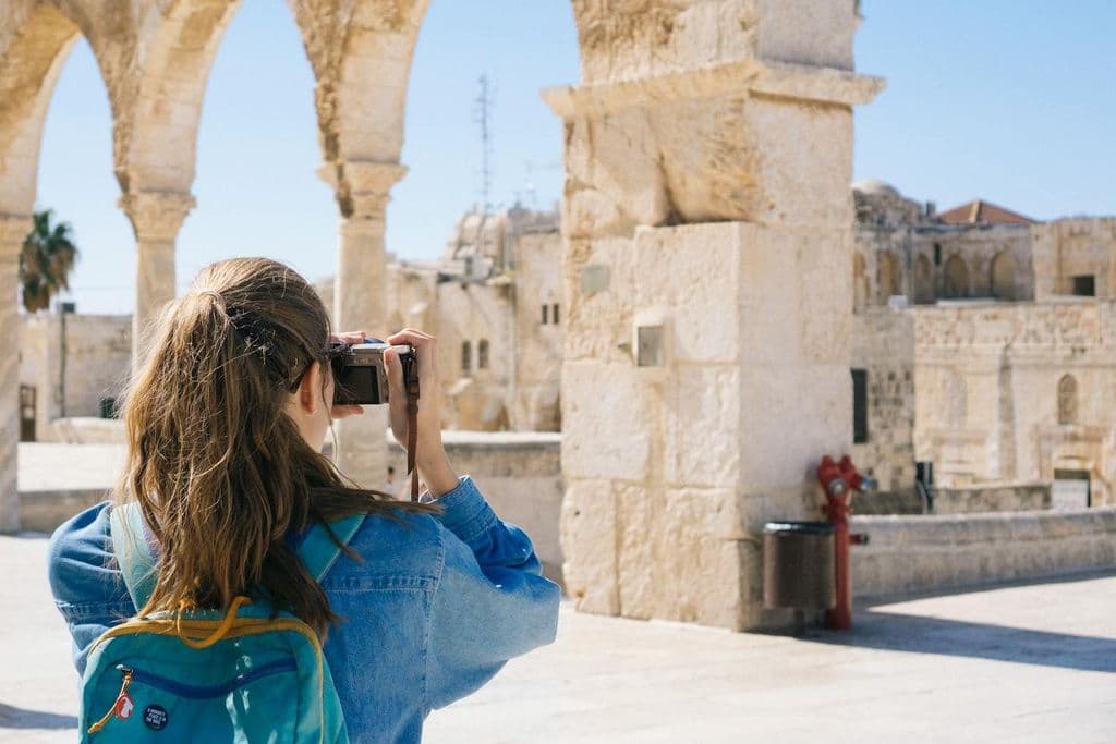 A woman photographs ruins.